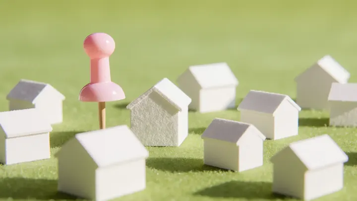 A giant lime map pin standing in an empty cobbled old-town square at golden hour