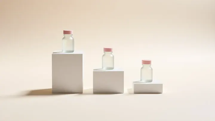 Three small glass bottles with pink caps on white plinths of different heights, like frames of a product animation