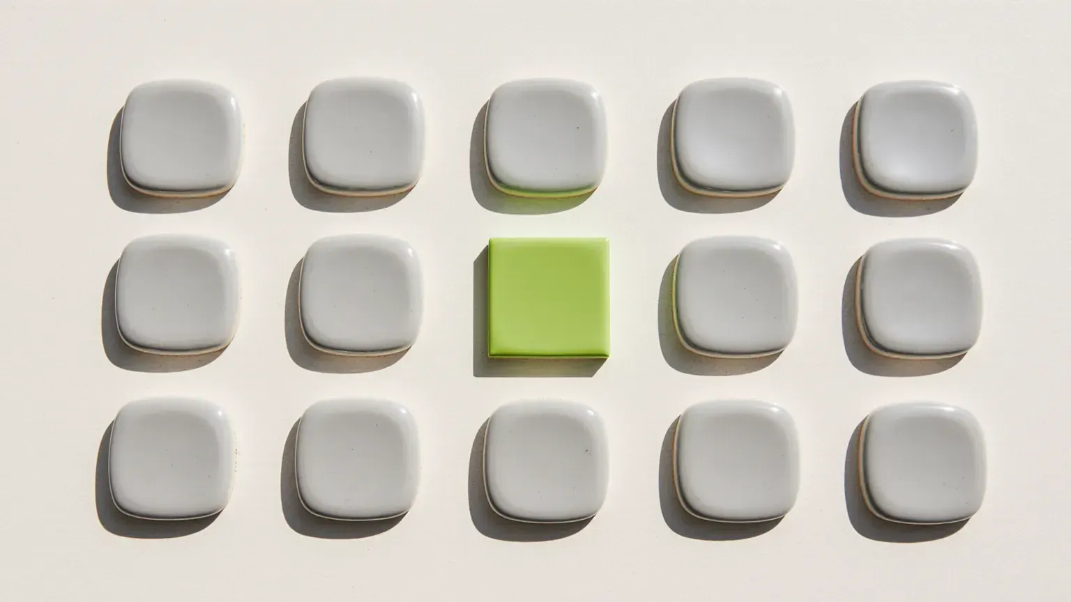 A neat grid of pale grey ceramic tiles with one lime green tile standing out, like an item flagged in an audit